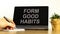 Form good habits symbol. Tablet with words `Form good habits`. Businessman hand with pen, house plant. Beautiful white backgroun