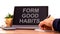 Form good habits symbol. Tablet with words `Form good habits`. Businessman hand with pen, house plant. Beautiful white backgroun