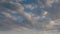 Formation and rapid movement of white clouds of different shapes in the blue sky in late spring at sunset.