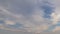 Formation and rapid movement of white clouds of different shapes in the blue sky in late spring at sunset.