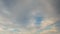 Formation and rapid movement of white clouds of different shapes in the blue sky in late spring at sunset.