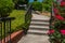 Formed concrete stairs and sidewalk with black iron railing, roses and groundcover