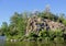 Former stone quarry. Summer landscape with a river, rocks, green grass, trees, and blue sky.