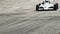 Formula 1 car passes by hot racing track tarmac