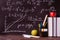 Formulas, chalk inscriptions on a black blackboard, books, pens, markers, apples on the table
