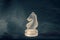 Forsted white glass knight chess piece on dramatic background