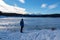 Forstsee - Rear view of man with hiking backpack watching the frozen lake Forstsee, Techelsberg, Carinthia (Kaernten), Austria,