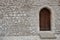 Fortress or castle wall made of stacked stone blocks and a wooden door with gothic style pointed arch