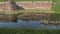 Fortress moat with water reflecting trees and castle walls. Bridge over the moat.