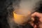 Fortune-telling on coffee. Close-up sorcerer hand holding a yellow mug with steam on a dark background