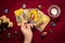 Fortuneteller`s hand with black manicure lays out tarot cards, crystal, candle, dry roses on red tablecloth