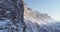 Forward aerial along snowy alpine steep rocky cliff valley.Sunny day,clear sky.Winter Dolomites Italian Alps mountains