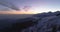 Forward aerial top view over winter snowy mountain road.Blue hour dusk or dawn twilight Alps mountains street path snow