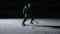 Forward in green uniform with stick in hands slides on ice and hitting puck. Man sliding on rink and cutting ice into