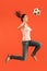 Forward to the victory.The young woman as soccer football player jumping and kicking the ball at studio on a red