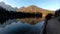 Forward walking on walkway at Laghi di Fusine lake with mountains reflected on calm water