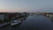 Forwards fly above boats on water surface in canal. Wide promenade along water at twilight. Copenhagen, Denmark