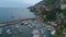 Forwards fly above boats and yachts moored in marina. Rocky slope rising from water. Mediterranean travel destination