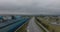 Forwards fly above road loading in industrial suburb on cloudy day. Large cylindrical tanks for materials in factory