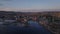 Forwards fly above water in bay at golden hour. Aerial view of buildings in city. Modern futuristic building of