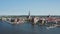 Forwards fly above water surface. Aerial view of historic part of town with tall spire of Saint Peters church