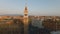 Forwards fly around historic tower with bells. Buildings in urban borough at golden hour. Rome, Italy