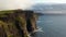 Forwards fly around rock wall. Revealing beautiful scenery of high vertical cliffs at sea coast. Cliffs of Moher