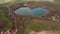 Forwards tilt up reveal of water surface in shape of heart and rural landscape next by lake. Aerial view from drone