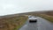 Forwards tracking of silver vintage sports car driving on wet road along moorlands. Autumn hazy weather. Ireland