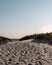 Fotsteps in the sand leads over the dunes, between some bushes, toward the ocean next to the Swedish coastal town called Lomma