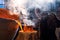 Foundry worker in a protective mask looks inside the vat in which the molten metal