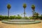 Fountain near Koutoubia Mosque minaret at medina quarter of Marrakesh, Morocco. There is beautiful green garden with palms. Blue