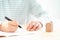 Fountain pen holding by man with small ceramic home model on desk