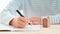 Fountain pen holding by man with small ceramic home model on desk