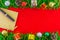 Fountain pen and notebook in the middle of strip frame with Christmas tree branches on red background for Christmas decoration.