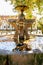 Fountain releasing water jets on a stone full of water and fallen leaves of trees