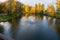 Fountain star on the lake with reflection of golden crowns birch on the shore. Novi Petrivtsi, Ukraine