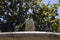 Fountain. Stone fountain filled with water with a jet of water at its tip in a park in Madrid on a clear day with a blue sky