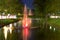 Fountain in water canal with nighttime light.