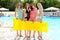 Four attractive girlfriends in colorful swimsuit with yellow inflatable mattress in the pool background