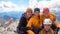 Four attractive women mountain climbers hug and smile on a mountain peak after a hard climb together