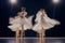 Four ballerinas twirl in unison, their white costumes blurring into a dreamy display of motion.