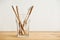 Four bamboo toothbrushes in a glass on a wooden table