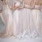 Four beautiful bridesmaid dresses in pastel colors are in each other`s arms. Back, close-up lace skirts