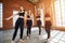 Four beautiful women in sportswear posing in various dance poses in a loft studio in large windows, laughing and talking