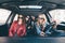 Four beautiful young cheerful women looking happy and playful while sitting in car