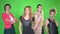 Four beautiful young women in stylish clothes posing at camera on green screen background