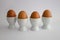 Four boiled eggs in egg cups, on white background