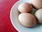 Four boiled eggs are placed on white plates.