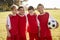 Four boys in a football team holding ball, smiling to camera